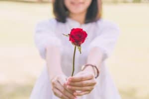 Girl holding out a single rose