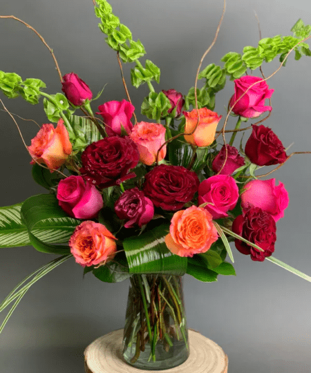 Not your average rose arrangement, this vase includes a mix of vibrant colored roses arranged with tropical greens and modern flair. 