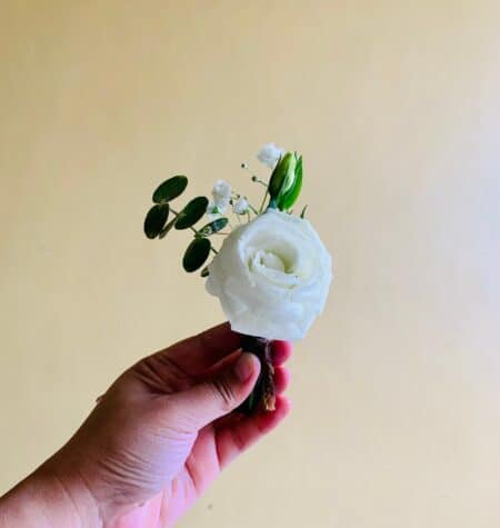Hand holding white boutonniere