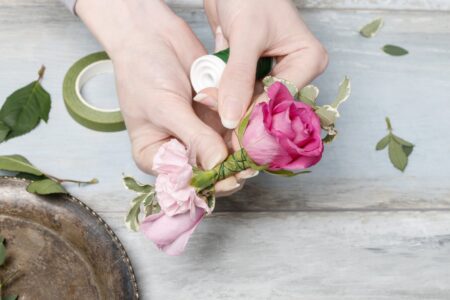 Hands making corsage with pink rose