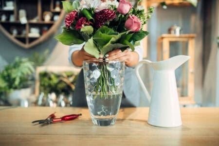 Female florist puts flower bouquet into a vase